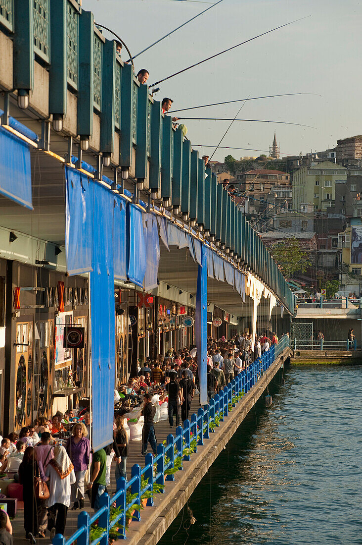 Looking along line of bars and restaurants on Galata Bridge with fishermen above, Istanbul, Turkey
