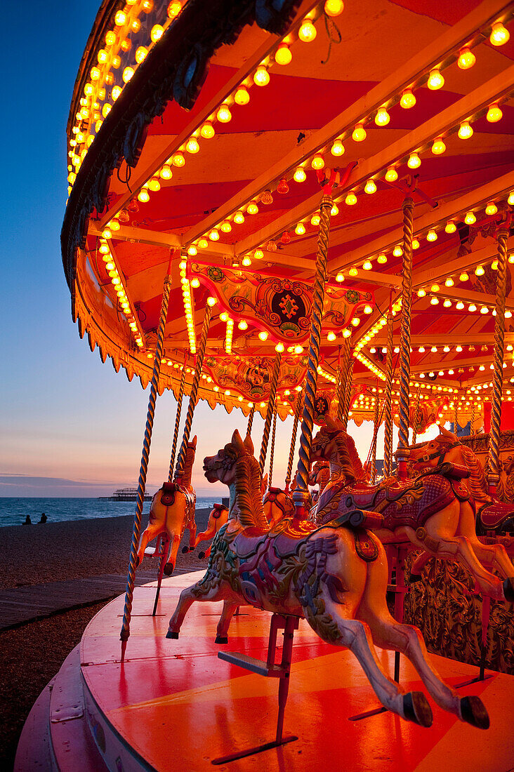 Merry-go-round on Brighton beach at dusk, East Sussex, UK