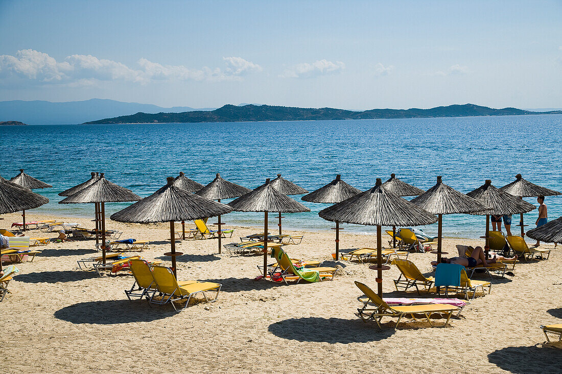 Beach umbrellas and chairs on tourist beach, Ouranoupoli, Halkidiki, Greece