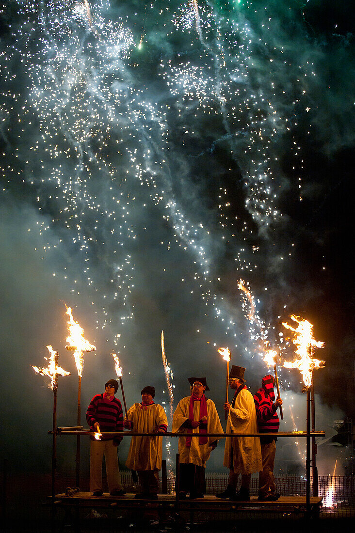 People dressed as clergy on stand with fireworks behind them at Newick Bonfire Night, East Sussex, England, UK