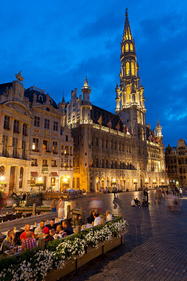 People at restaurant tables at dusk in Grand Place, Brussels, Belgium