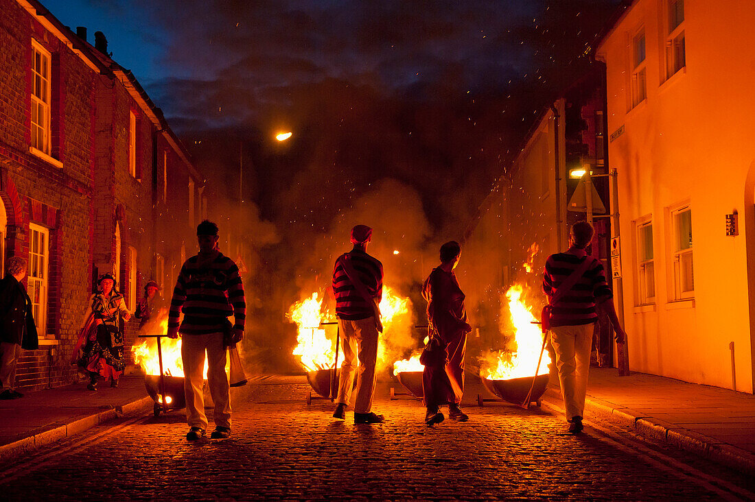 People dressed as smugglers carrying burning carts down street, Lewes, East Sussex, England, UK