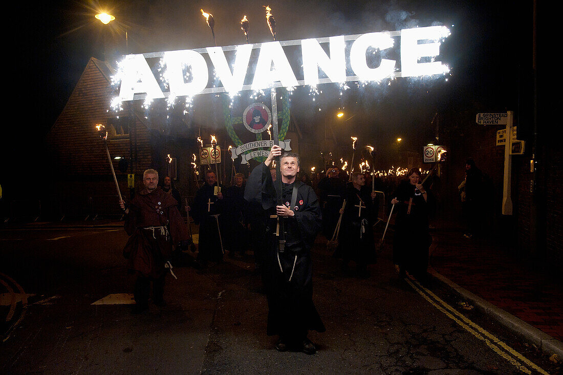 Man dressed as monk carrying 'Advance' banner on Bonfire Night, Lewes, East Sussex, England