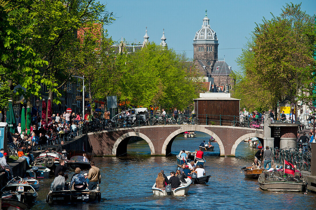 Tourboats going along canal with St Nicholas Church in background, Amsterdam, Holland