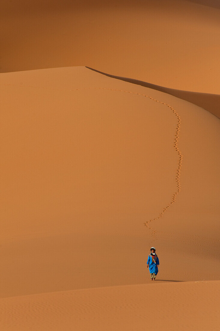 Berber 'Blue man' walking across sand dunes in Erg Chebbi near Merzouga, Sahara Desert, Morocco