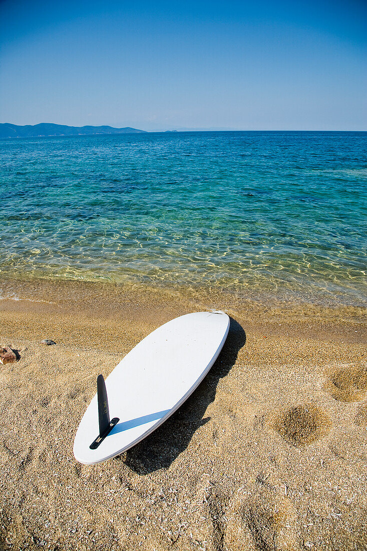 Surfboard and footprints on beach, Ierissos, Halkidiki, Greece