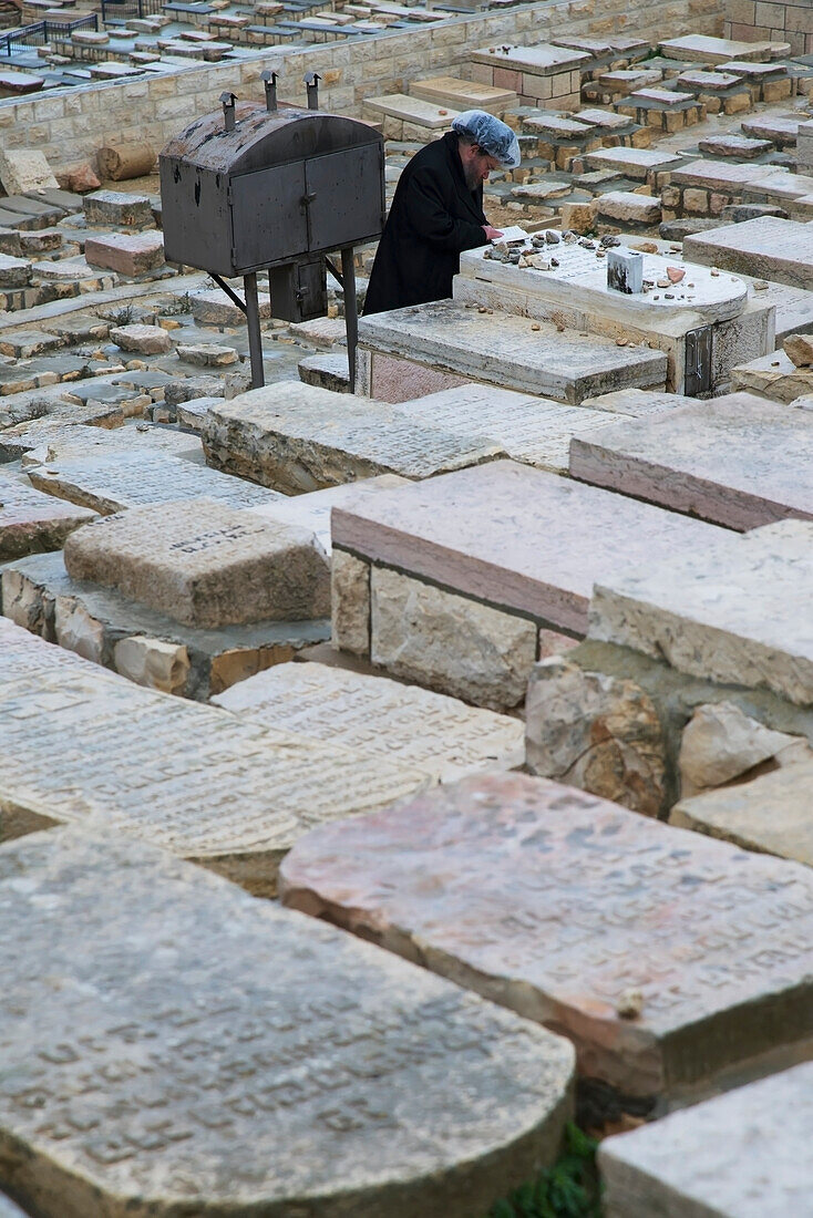 Orthodox Jew praying at tomb at Mount of Olives cemetery, Jerusalem, Israel