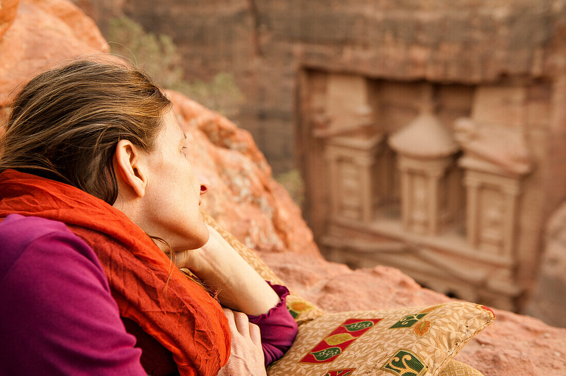 Woman lying on rock, Al Khazneh in background, Petra, Jordan, Middle East
