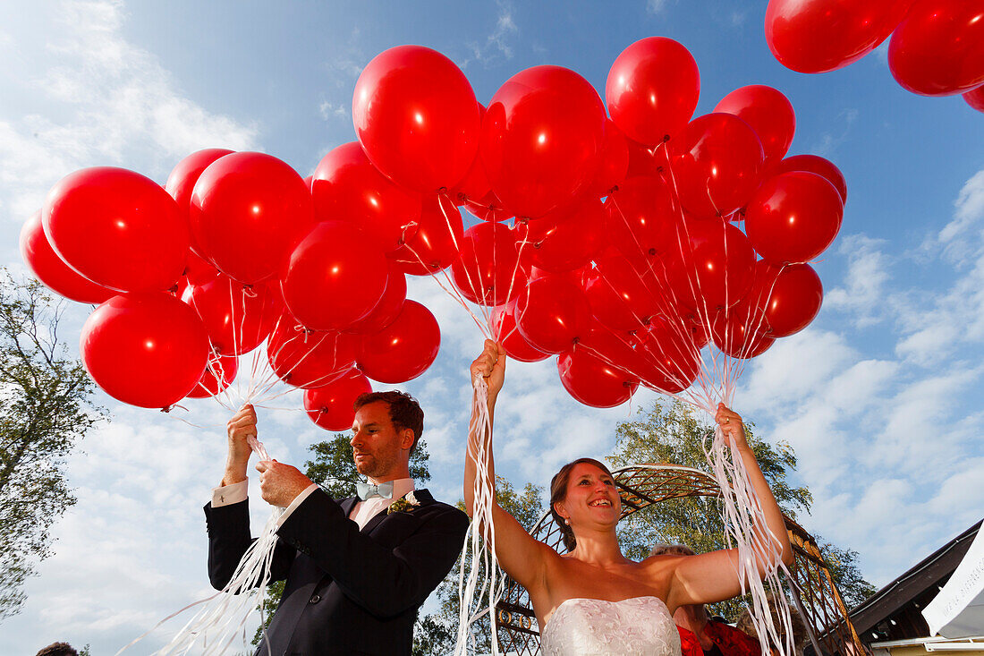Brautpaar lässt rote Luftballons fliegen, Bayern, Deutschland