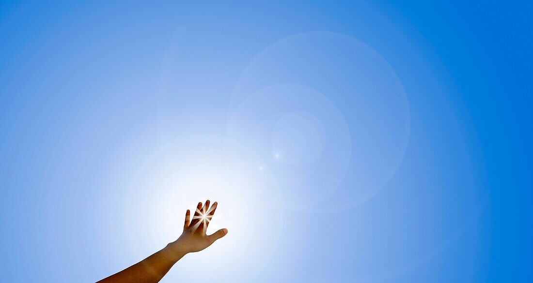 Arm and hand reaching out to sun