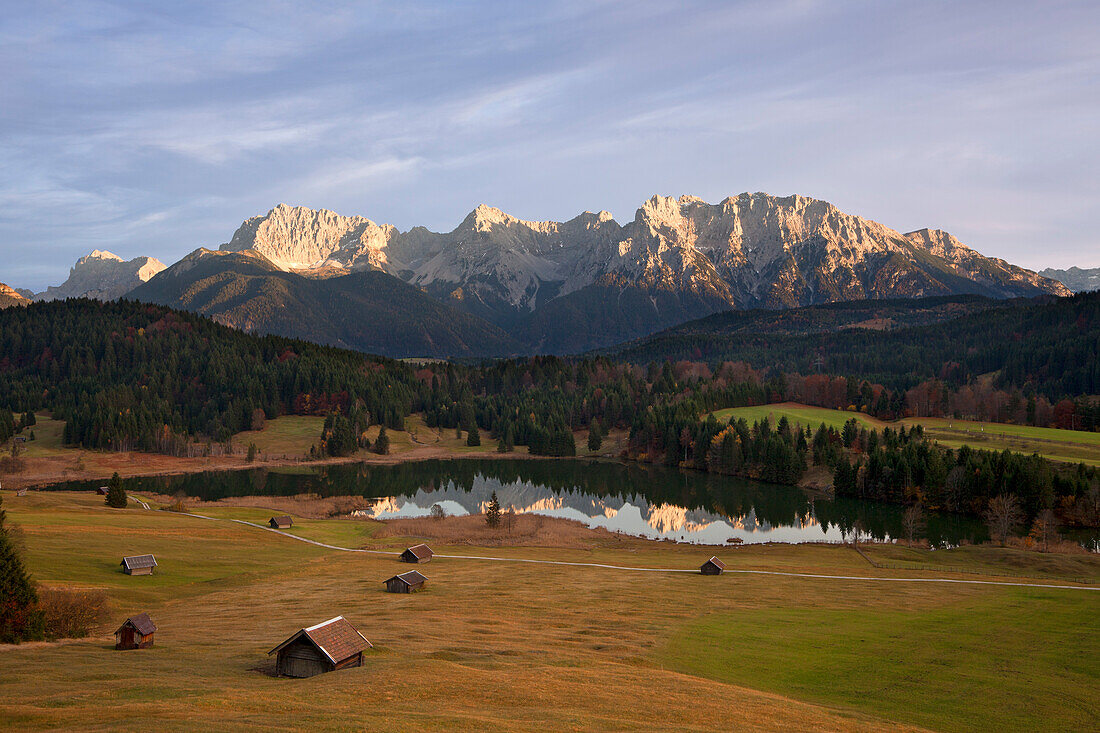 Almwiese mit Heustadeln, Blick über den Geroldsee auf das Karwendelgebirge, bei Mittenwald, Bayern, Deutschland