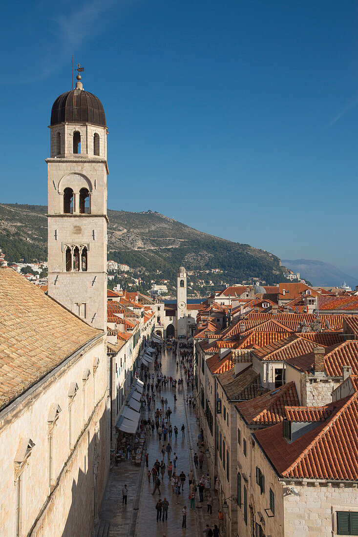 Blick von der Stadtmauer auf Fußgänger in der Stradun Hauptgasse der Altstadt mit Kirchturm von Franziskanerkloster, Dubrovnik, Dalmatien, Kroatien, Europa