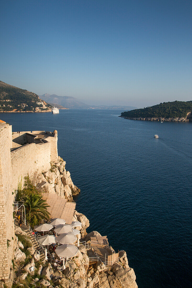 Sonnenschirme an einem Café an der Küste unterhalb der Stadtmauer der Altstadt, Dubrovnik, Dalmatien, Kroatien, Europa