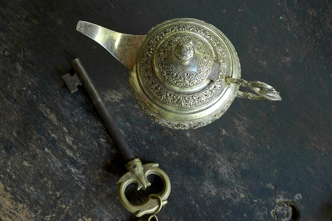 Ornate, silver coloured tea pot and huge room key at the Eco-Resort The Samadhi Center, resort in the mountains near Kandy, Sri Lanka