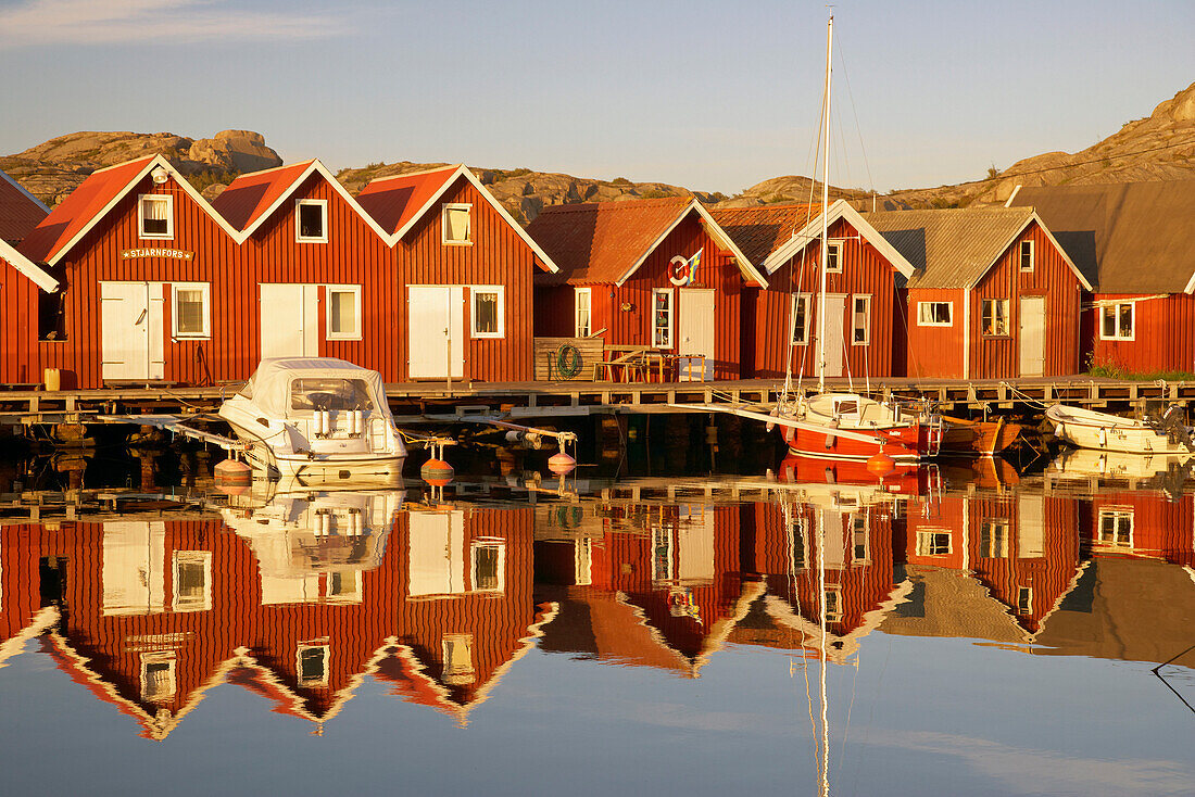 Boats and boot houses in Bleket port reflecting in the water, Tjoern Island, Province of Bohuslaen, West coast, Sweden, Europe