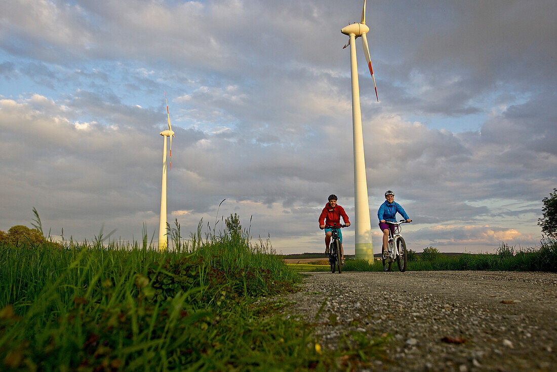 Zwei Fahrradfahrer fahren mit Elektrofahrrädern zwischen Feldern, Tanna, Thüringen, Deutschland