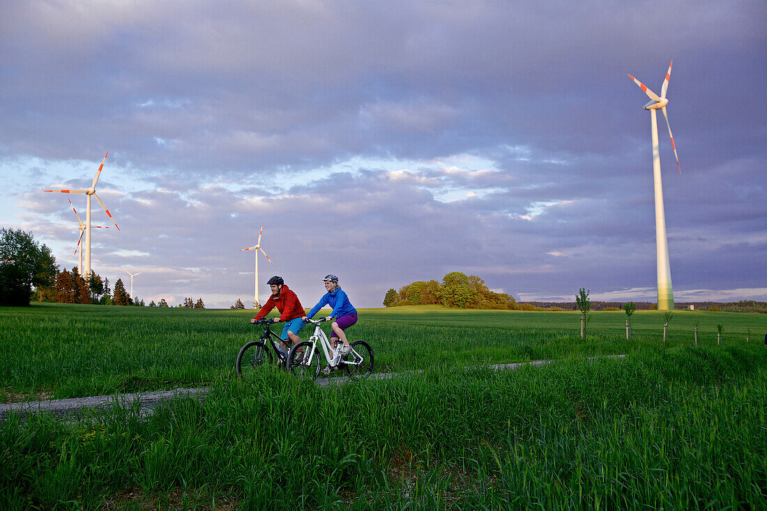 Zwei Fahrradfahrer fahren mit Elektrofahrrädern zwischen Feldern, Tanna, Thüringen, Deutschland