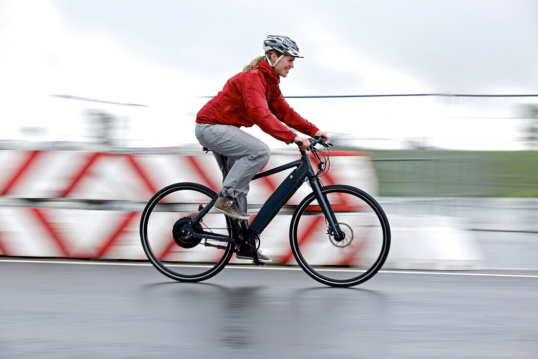 Woman riding an electric bicycle on a test track, Tanna, Thuringia, Germany