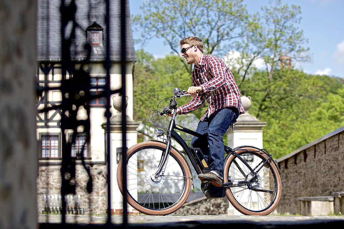 Young man riding an electric bicycle in a city, Tanna, Thuringia, Germany