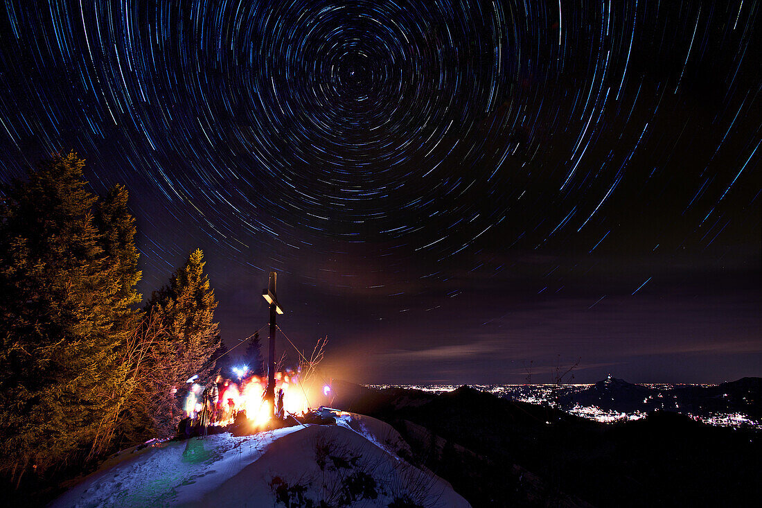 Group of people standing around a campfire beside a summit cross at night, Grasgehren, Obermaiselstein, Bavaria, Germany