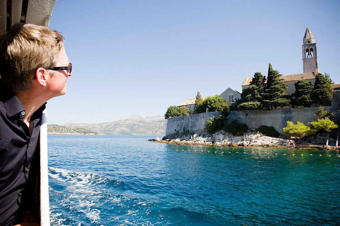 Man on a ferry looking at Franciscan monastery, Lopud, Elaphites, Dubrovnik-Neretva, Croatia