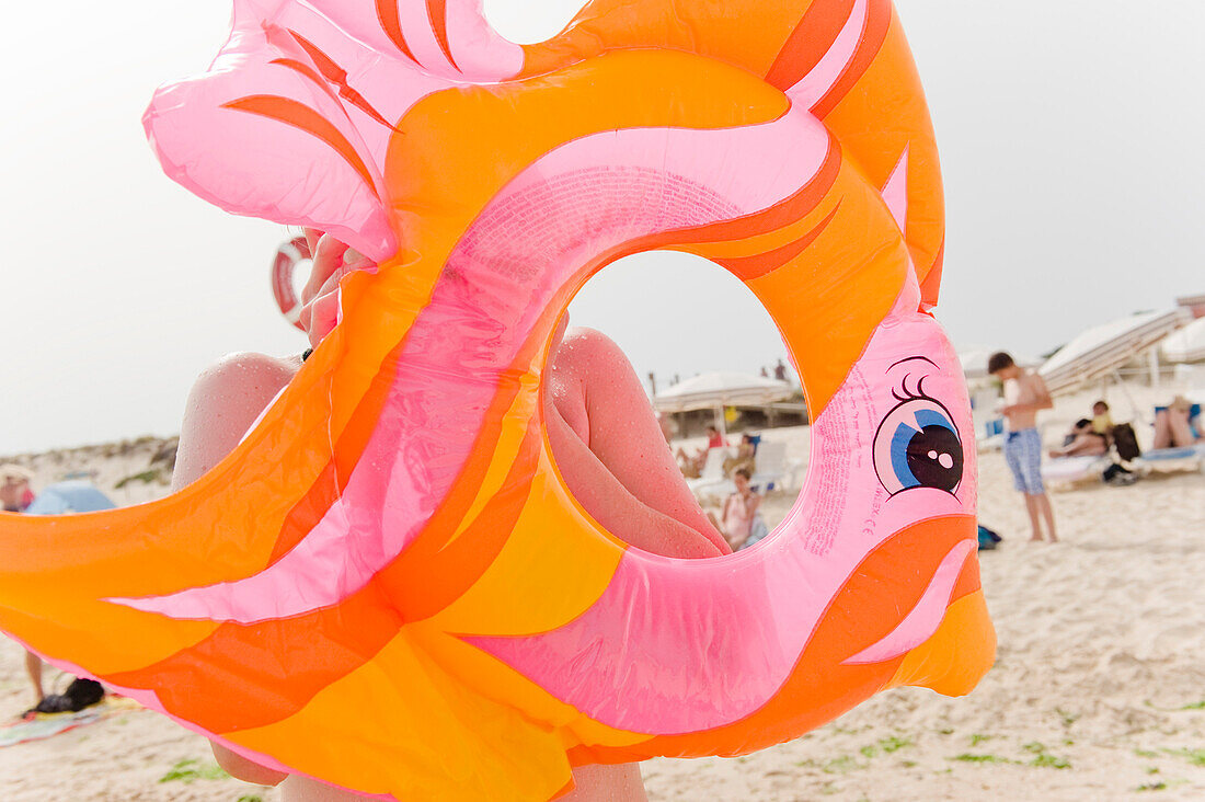 Child blowing up a floating tire at beach, Algarve, Portugal