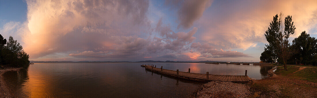 Jetty at the lake shore, clouds at sunset, Castiglione del Lago, Lago Trasimeno, province of Perugia, Umbria, Italy, Europe