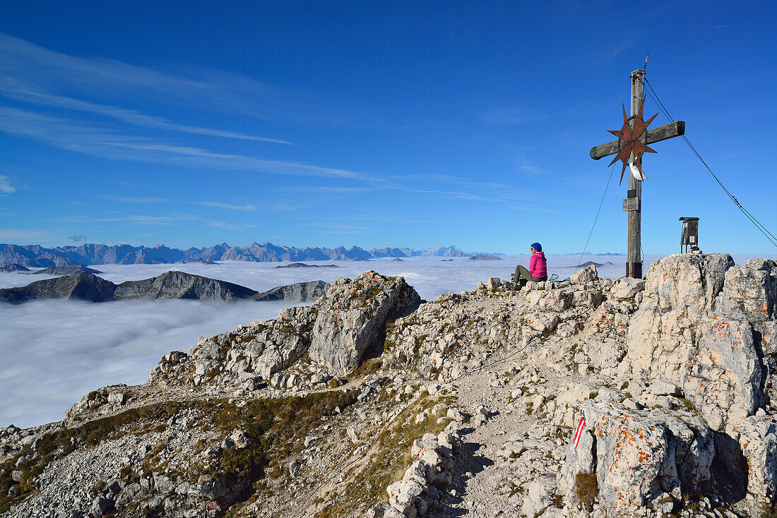 Woman sitting at summit of Guffert, mountain range in background, Brandenberg Alps (Rofan), Tyrol, Austria