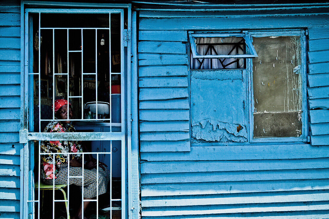 Frau sitzt hinter vergitterter Tür in ihrer Hütte, Township Langa, Kapstadt, Südafrika, Afrika