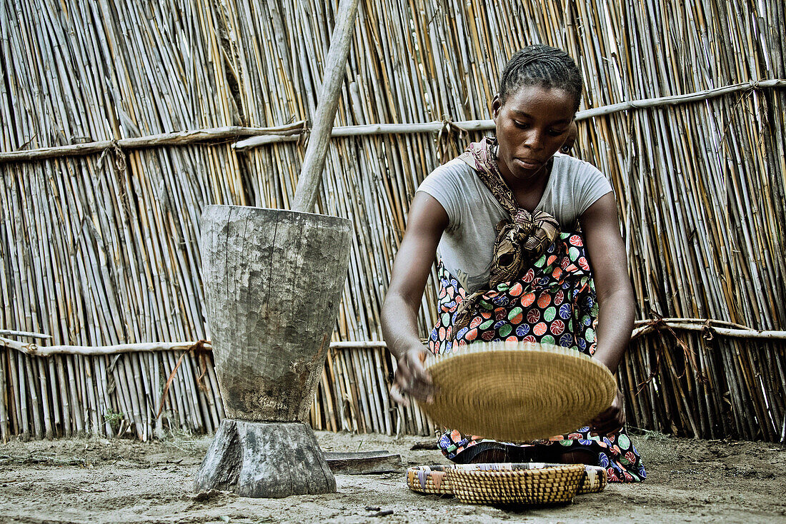 Young mother from the Lozi tribe with baby sifting grain, Caprivi region, Namibia, Africa