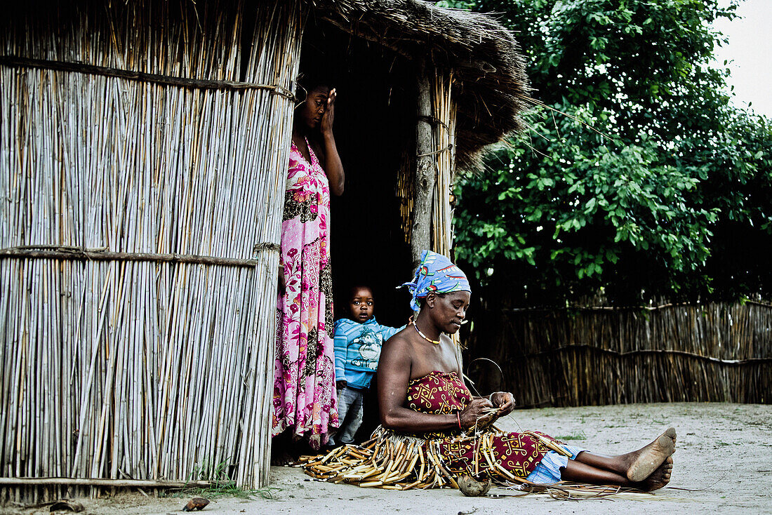 Two women and a child from the Lozi tribe in front of their hut, Caprivi region, Namibia, Africa
