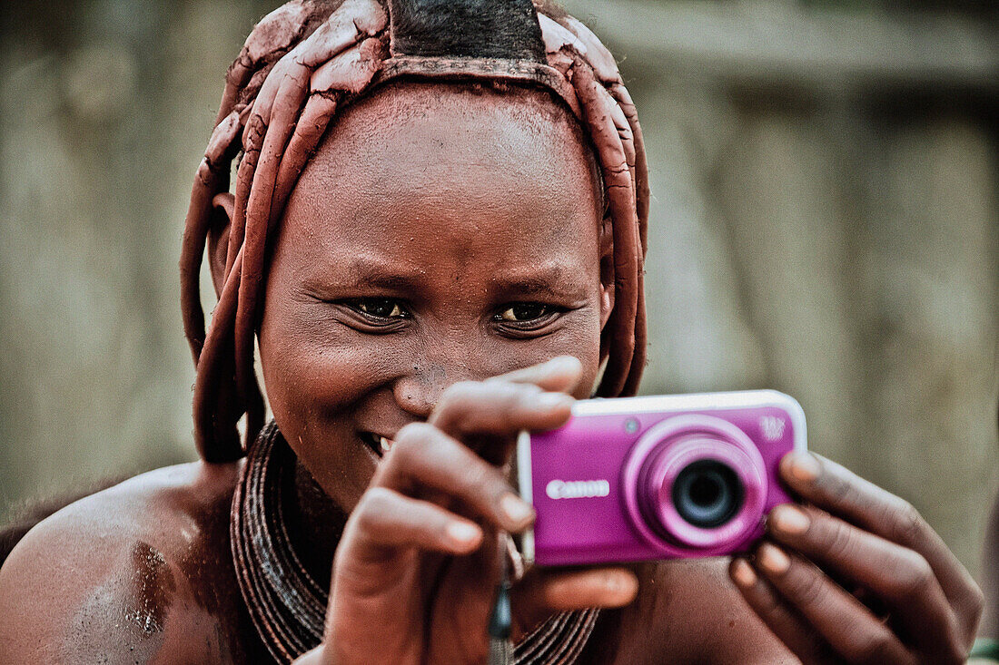 Woman of the Himba tribe holding a modern camera, Kaokoland, Namibia, Africa