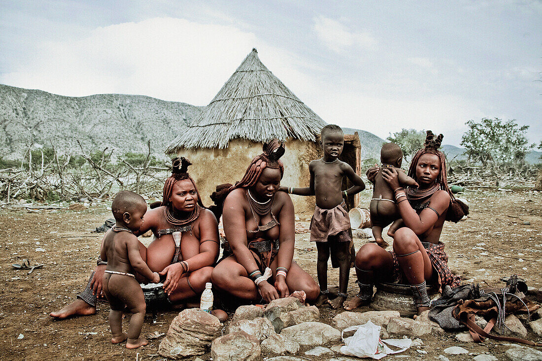 Three women and three children of the Himba tribe sitting at a campfire, Kaokoland, Namibia, Africa
