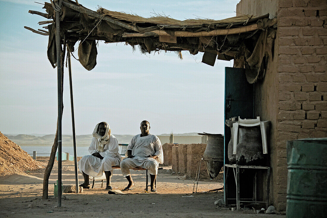 Zwei Männer vor ihrer Hütte in Wadi Halfa, im Hintergrund der Nil, Sudan, Afrika