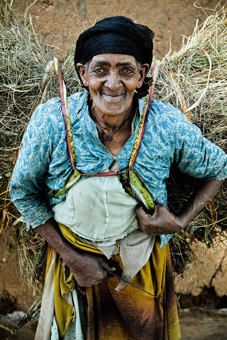 Alte Frau von der Dorze Volksgruppe trägt ein Bündel Heu, Südäthiopien, Afrika