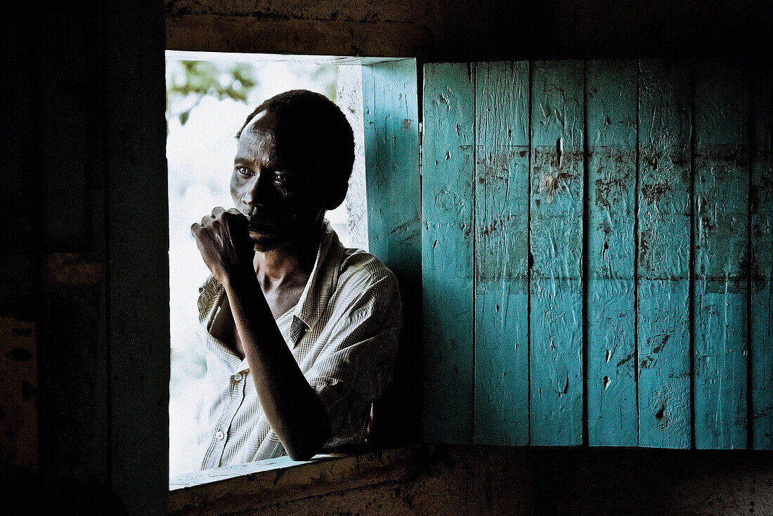 Man standing at the window of his hut, Uganda, Africa
