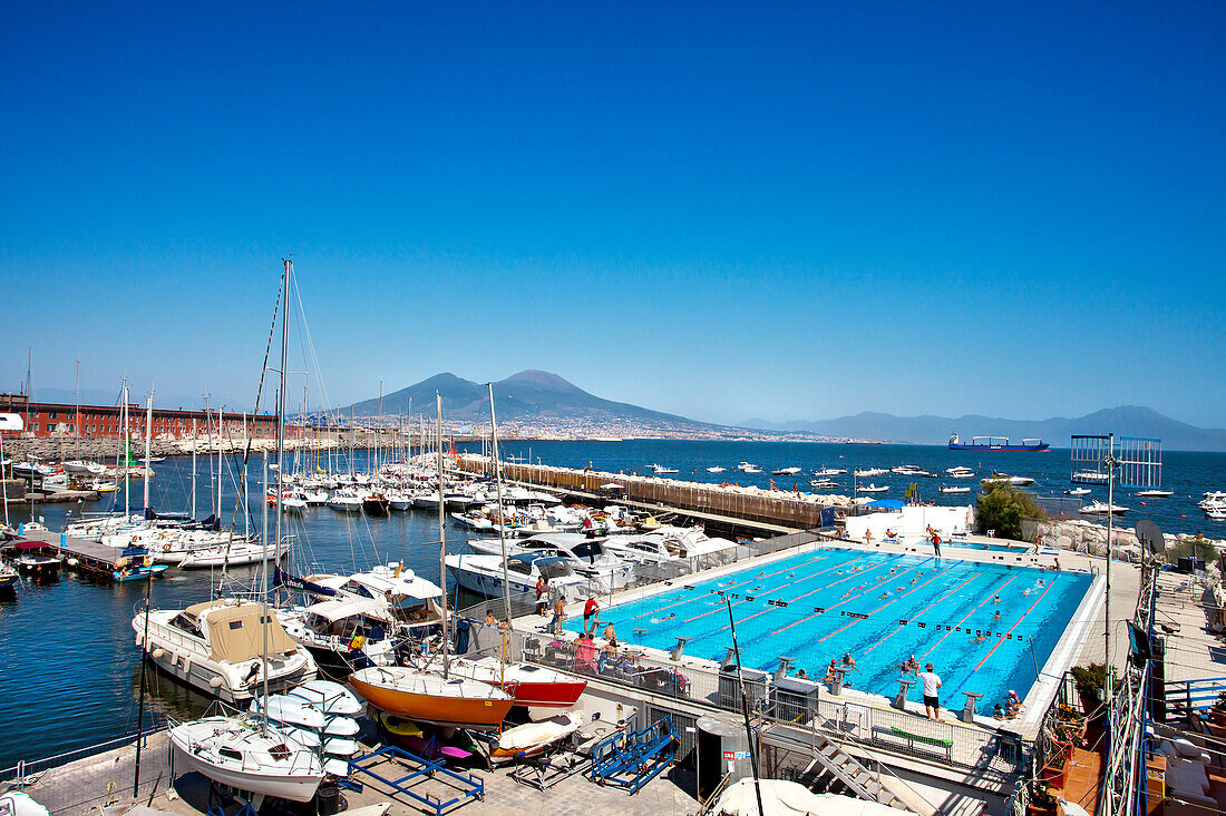 View over swimming pool and harbour towards Vesuvius, Naples, Bay of Naples, Campania, Italy