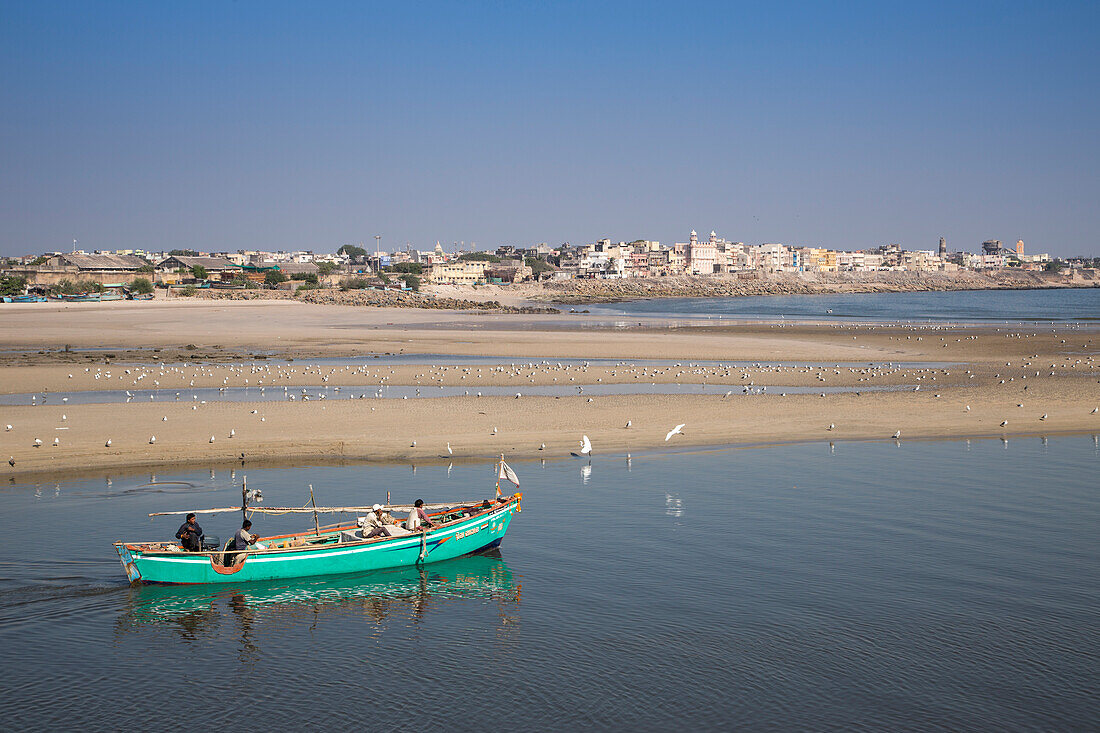 Fischerboot und Seevögel am Strand in der Einfahrt zum Hafen, Porbandar, Gujarat, Indien