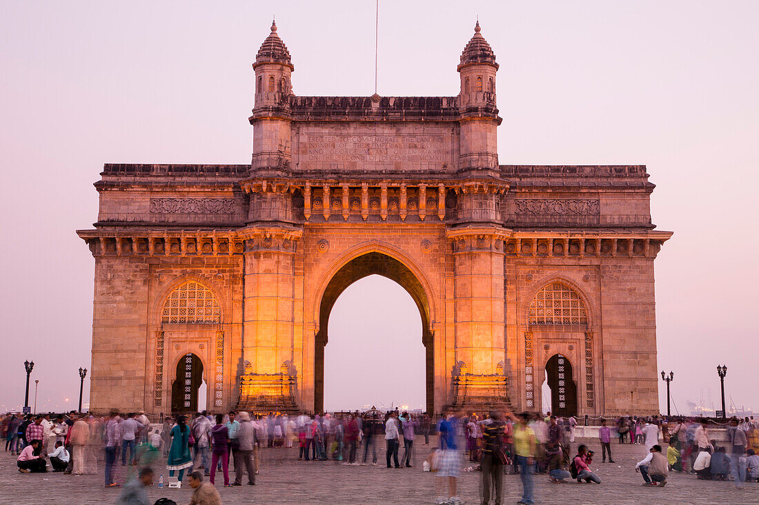Menschen vor dem Torbogen Gateway to India in der Abenddämmerung, Mumbai, Maharashtra, Indien