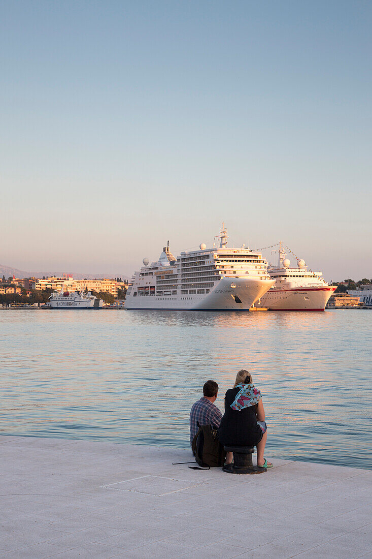 Couple at the pier with cruise ships MV Silver Spirit, Silversea Cruises, and MS Deutschland in the distance, Split, Split-Dalmatia, Croatia