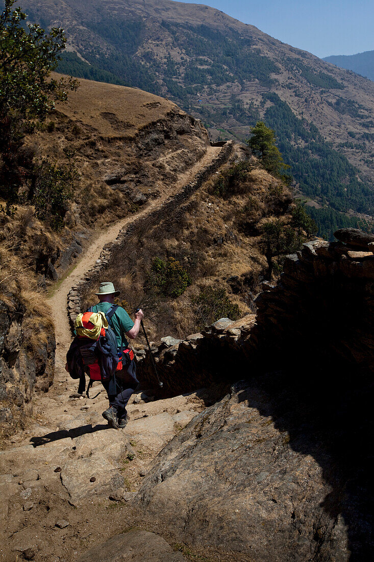 A trekker descends a steep set of hillside stone stairs in Nepal Solukhumbu Region, Nepal