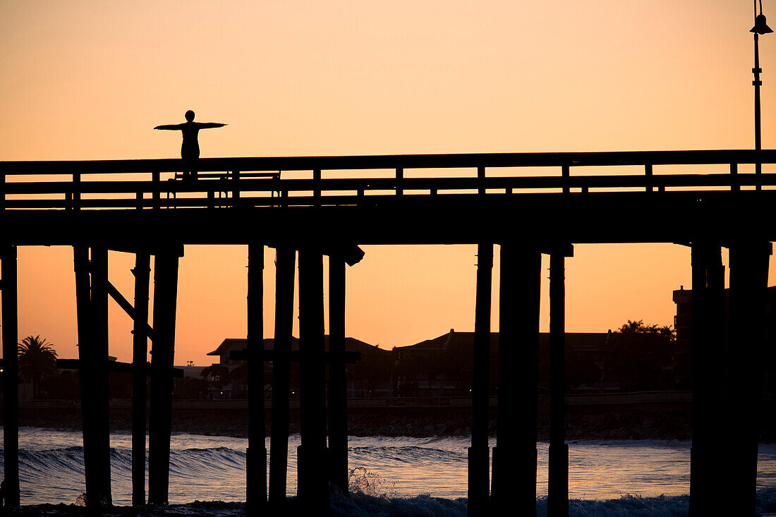 A silhouetted woman does a yoga pose on the Ventura Pier in Ventura, California Ventura, California, United States of America