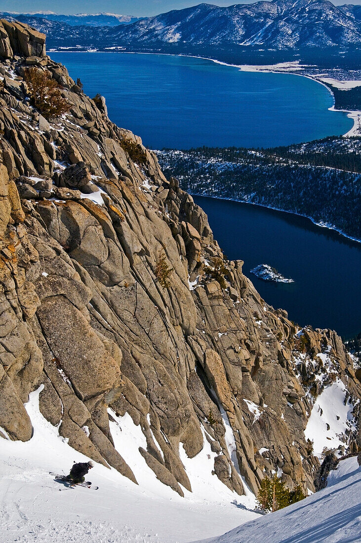 A skier descends Emerald Chute high above Emerald Bay and Lake Tahoe in the winter, CA Lake Tahoe, California, USA