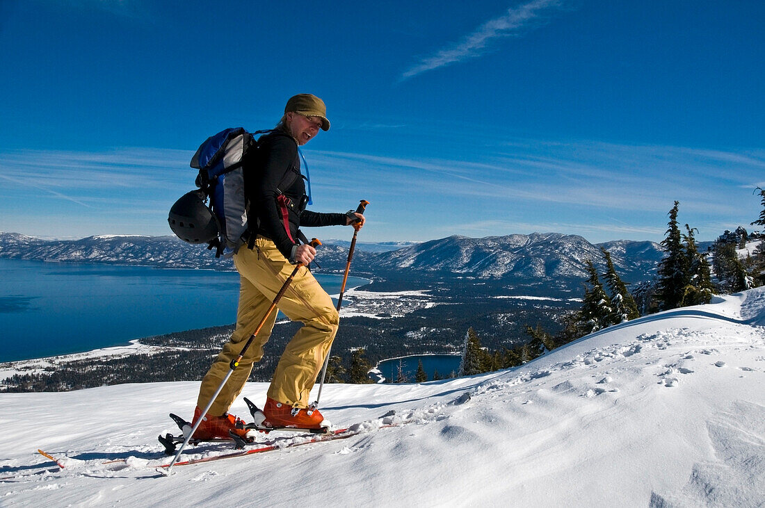 A female skier skins up Mount Tallac with Lake Tahoe in background, CA Lake Tahoe, California, USA