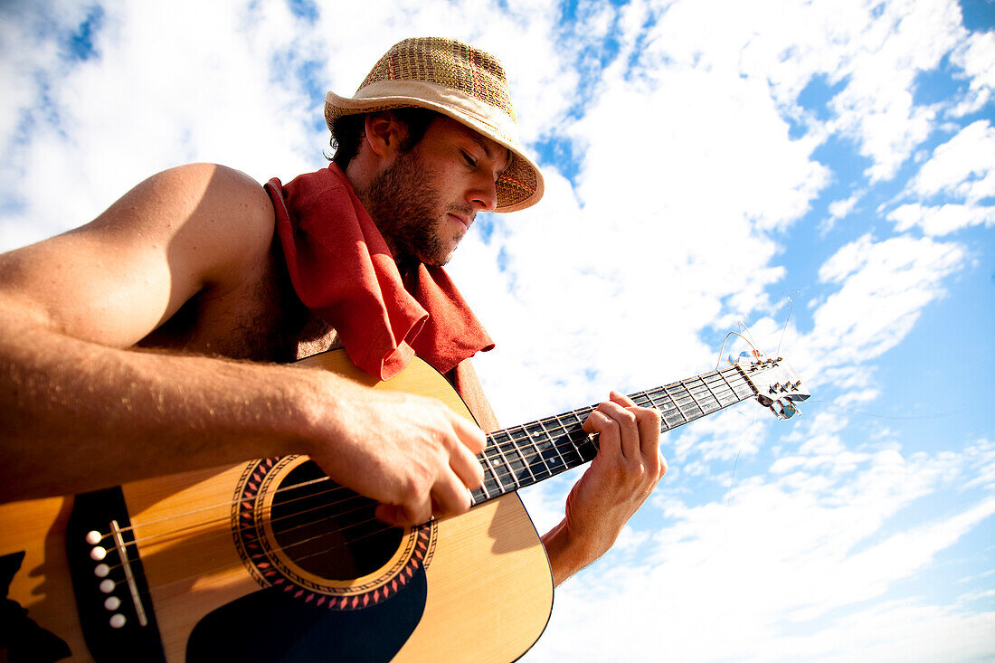 A young man plays his guitar while on a fishing boat off the coast of Malakati, Fiji Malakati, Nacula, Fiji