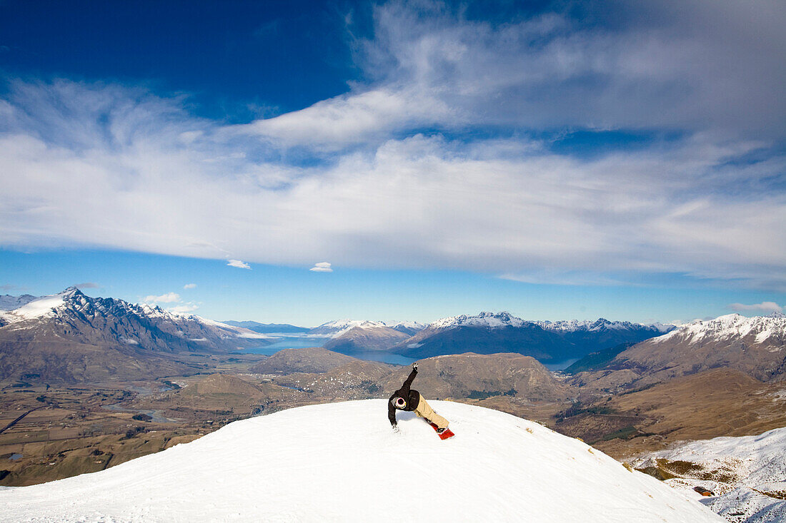 A male snowboarder blasts a heel side turn while snowboarding in Queenstown, New Zealand Queenstown, Otago, New Zealand