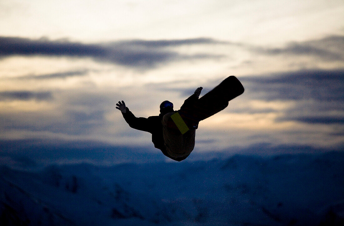 A male snowboarder does a back flip while riding at a snow park in Wanaka, New Zealand Wanaka, Otago, New Zealand