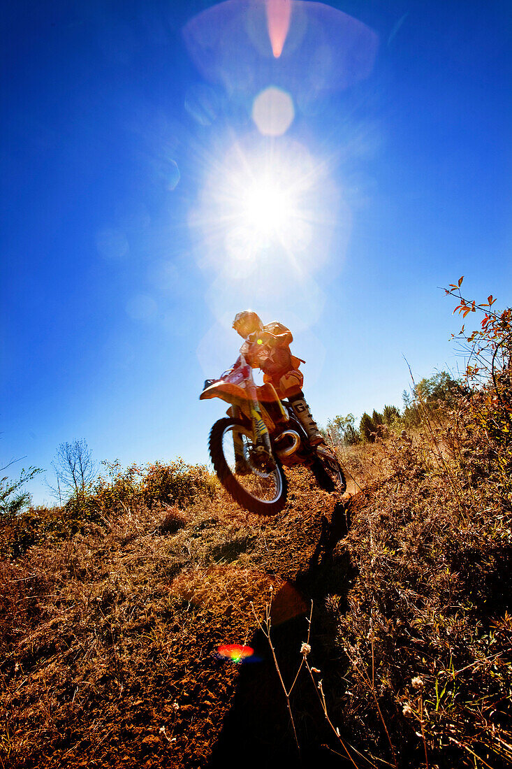 A motorcyclist catches air on a jump during an Enduro race in Maplesville, Alabama. (Back lit, Lens Flare), Maplesville, Alabama, United States