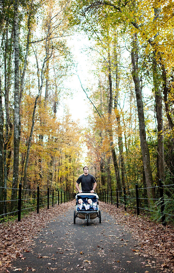 A man runs on a greenway in the fall with his twin sons in a stroller Helena, Alabama, United States