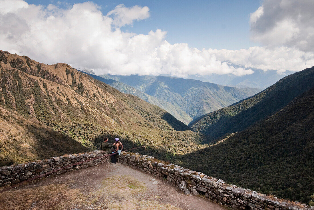 A young couple enjoys themselves at a lookout point along the Inca Trail amongst ancient ruins Inca Trail, Andes Mountains, Peru